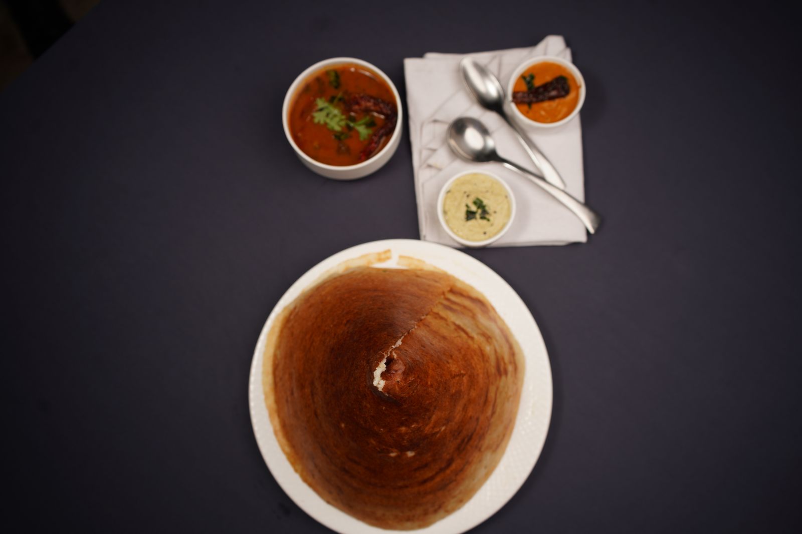 Top view of a South Indian dosa meal with chutneys and sambar